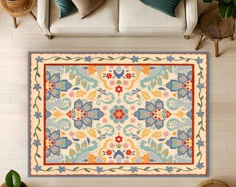 May include: A rectangular area rug featuring a cream background with a symmetrical floral pattern in shades of blue, red, yellow, and light green. The rug has a decorative border with a repeating blue flower vine and a thin red frame.