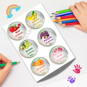 May include: A sheet of colorful fruit stickers, each in a bubble design, with English and Thai text. The stickers feature fruits like strawberries, grapes, and oranges, labeled with colors such as red, yellow, and purple. A rainbow and handprints are also visible.