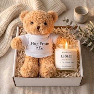 May include: A gift box with a teddy bear wearing a white t-shirt printed with "Hug From Afar". A lit candle with the text "Sending You Light" is also in the box. The candle is 255 grams.