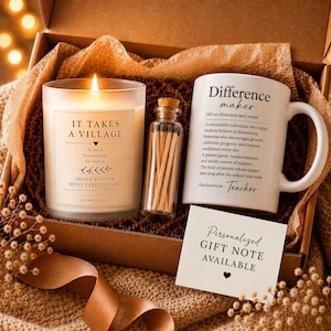 May include: A gift box containing a lit candle in a glass jar labeled IT TAKES A VILLAGE, a small glass bottle filled with wooden matches, and a white ceramic mug with the text Difference maker and Teacher. A card reads PERSONALIZED GIFT NOTE AVAILABLE.