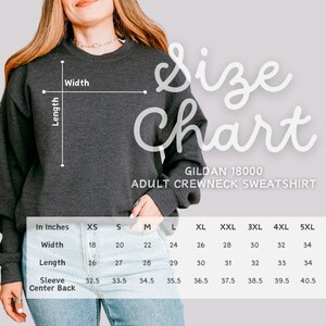 Puede incluir: Tabla de tallas para una sudadera con cuello redondo para adultos Gildan 18000. La tabla muestra las medidas en pulgadas para el ancho, la longitud, la manga y la espalda para las tallas XS a 5XL.