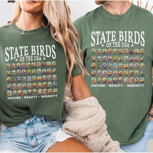 May include: Two green t-shirts with a white graphic of the state birds of the USA. The graphic includes the name of each bird and its state. The text below the graphic reads "Nature - Beauty - Serenity".