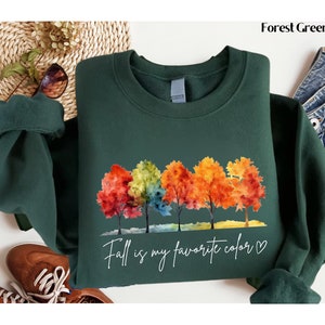 May include: Forest green sweatshirt with a watercolor design of colorful trees and the text "Fall is my favorite color &hearts;".