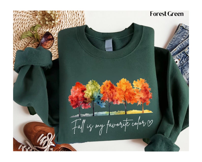 May include: Forest green sweatshirt with a watercolor design of colorful trees and the text "Fall is my favorite color &hearts;".