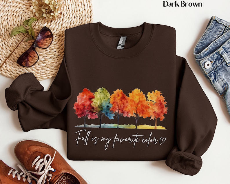 May include: Dark brown sweatshirt with a watercolor design of five colorful trees and the text "Fall is my favorite color" with a heart.