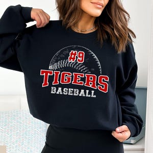 May include: Black sweatshirt with a white baseball graphic and the text "#9 TIGERS BASEBALL" in red.