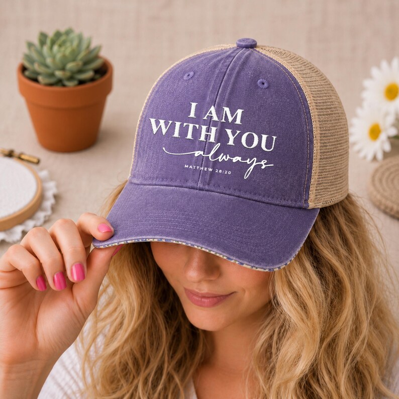 May include: A purple and tan baseball cap with the text "I AM WITH YOU always" in white. The cap has a mesh back and a curved brim. The text "Matthew 28:20" is below the main text.