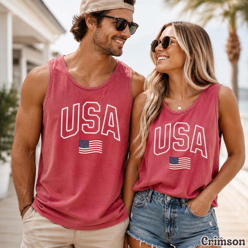 Peut inclure: Deux d&eacute;bardeurs cramoisis avec le mot "USA" en lettres blanches et un petit drapeau am&eacute;ricain. Les d&eacute;bardeurs sont port&eacute;s par deux personnes, dont une portant des lunettes de soleil et une casquette de baseball.