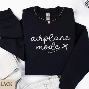 Puede incluir: Sudadera negra con el texto "airplane mode" y un peque&ntilde;o avi&oacute;n gr&aacute;fico en blanco.