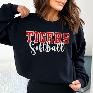 May include: Black sweatshirt with the text "TIGERS Softball" in red and white lettering.