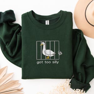 a green shirt with a picture of a duck in a cage