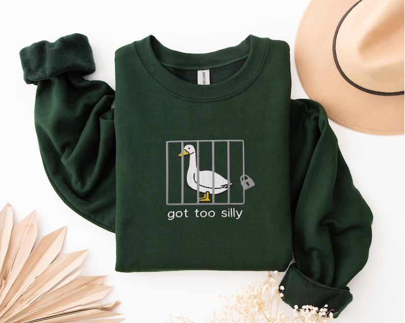 a green shirt with a picture of a duck in a cage