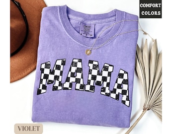 May include: A purple t-shirt with a checkered "MAMA" graphic. The shirt is made of a soft, comfortable material and has a distressed look. The shirt is available in a variety of colors.