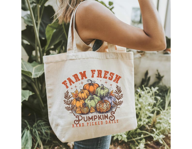 May include: A white canvas tote bag with the text "Farm Fresh" and a graphic of pumpkins. The text "Pumpkins" is below the graphic and the text "Hand Picked Daily" is below that.