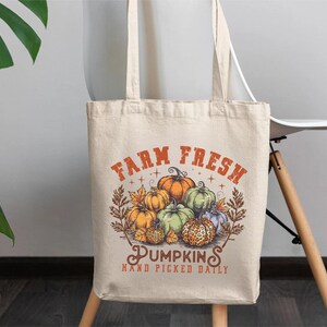 May include: A beige tote bag with a graphic of pumpkins and the text "Farm Fresh Pumpkins Hand Picked Daily".