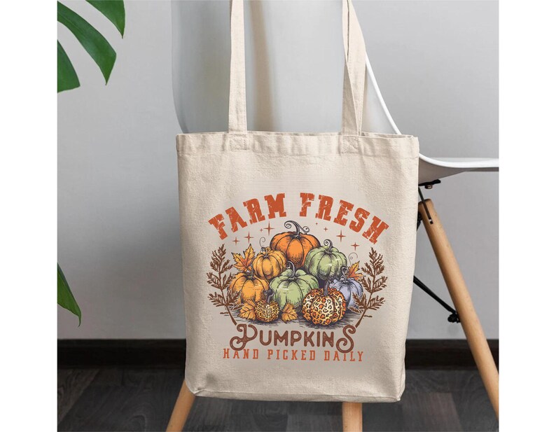 May include: A beige tote bag with a graphic of pumpkins and the text "Farm Fresh Pumpkins Hand Picked Daily".