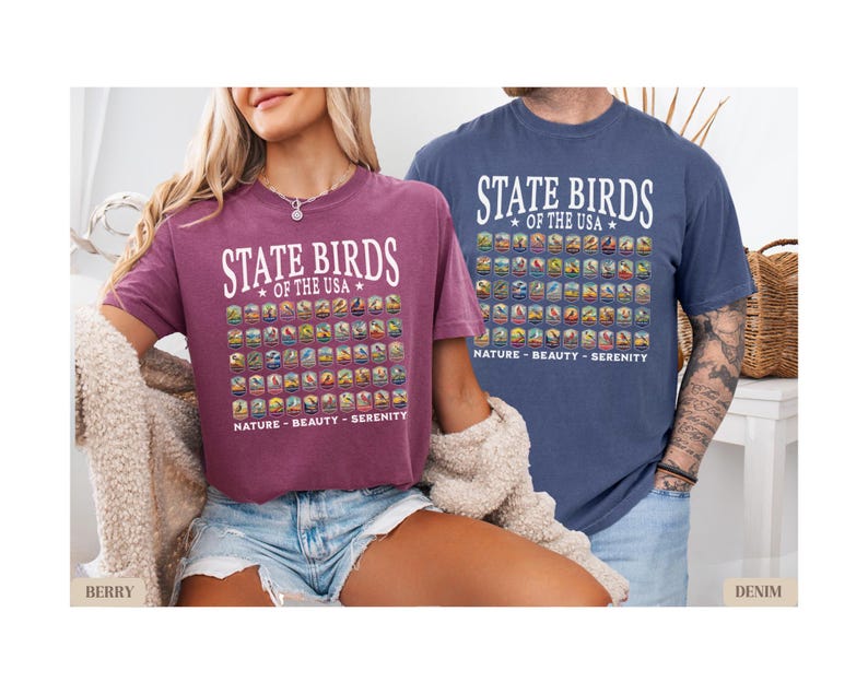 May include: Two t-shirts with a graphic design of state birds of the USA. The text on the shirts reads "State Birds of the USA" and "Nature - Beauty - Serenity". The shirt on the left is a berry color and the shirt on the right is denim blue.