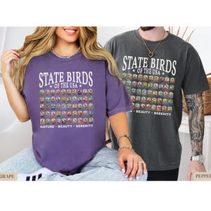 May include: Two people wearing purple and gray t-shirts with a graphic of all the state birds of the USA. The text on the shirts reads "State Birds of the USA".
