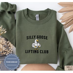 May include: Green sweatshirt with the text "Silly Goose Lifting Club" and an illustration of a goose lifting weights. The sweatshirt is embroidered.