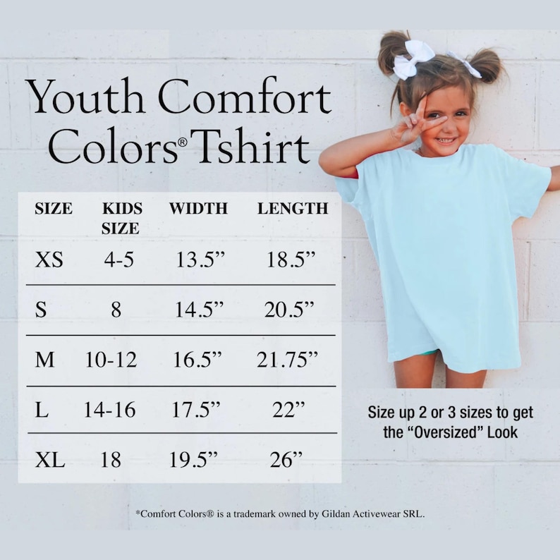 Puede incluir: Una camiseta juvenil azul claro con una tabla de tallas. La tabla enumera las tallas XS a XL, con medidas de ancho y largo en pulgadas. El texto "Youth Comfort Colors Tshirt" est&aacute; en la parte superior. Una ni&ntilde;a peque&ntilde;a lleva la camiseta.