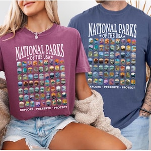 以下が含まれることがあります： アメリカの国立公園のグラフィックプリントが施されたTシャツ2枚。両方のTシャツに「National Parks of the USA」の文字がプリントされています。Tシャツは色が異なり、1枚はマルーン、もう1枚はブルーです。グラフィックプリントには、アメリカの国立公園のロゴがすべて含まれています。両方のTシャツのグラフィックプリントの下には、「Explore - Preserve - Protect」の文字がプリントされています。
