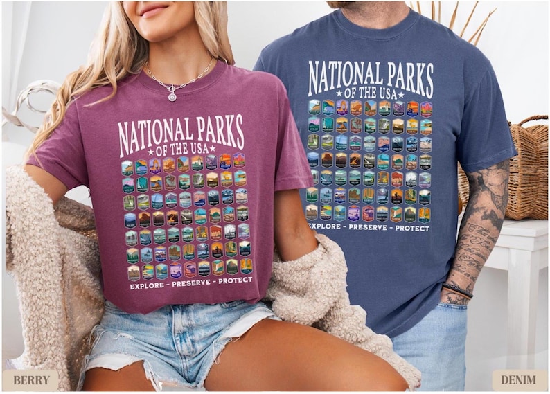 以下が含まれることがあります： アメリカの国立公園のグラフィックプリントが施されたTシャツ2枚。両方のTシャツに「National Parks of the USA」の文字がプリントされています。Tシャツは色が異なり、1枚はマルーン、もう1枚はブルーです。グラフィックプリントには、アメリカの国立公園のロゴがすべて含まれています。両方のTシャツのグラフィックプリントの下には、「Explore - Preserve - Protect」の文字がプリントされています。
