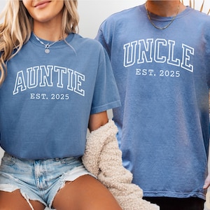 May include: Two blue jean t-shirts with white text. The first shirt says "Auntie Est. 2025" and the second shirt says "Uncle Est. 2025".