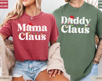 May include: Two t-shirts with Christmas themed text. The red shirt says "Mama Claus" with a Santa hat and string lights. The green shirt says "Daddy Claus" with a Santa hat and string lights.
