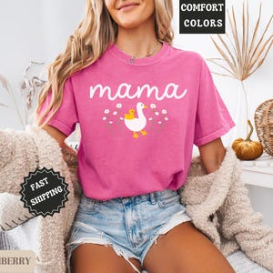May include: Pink t-shirt with the word "mama" and a graphic of a goose with a baby goose. The shirt is made of a soft, comfortable fabric.