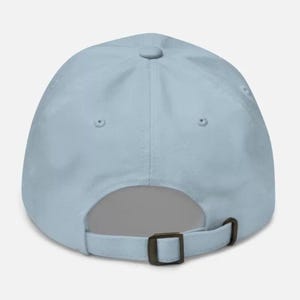 May include: A light blue baseball cap with a brown adjustable strap.