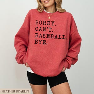 May include: Red sweatshirt with the text "SORRY. CAN'T. BASEBALL. BYE." printed in black.