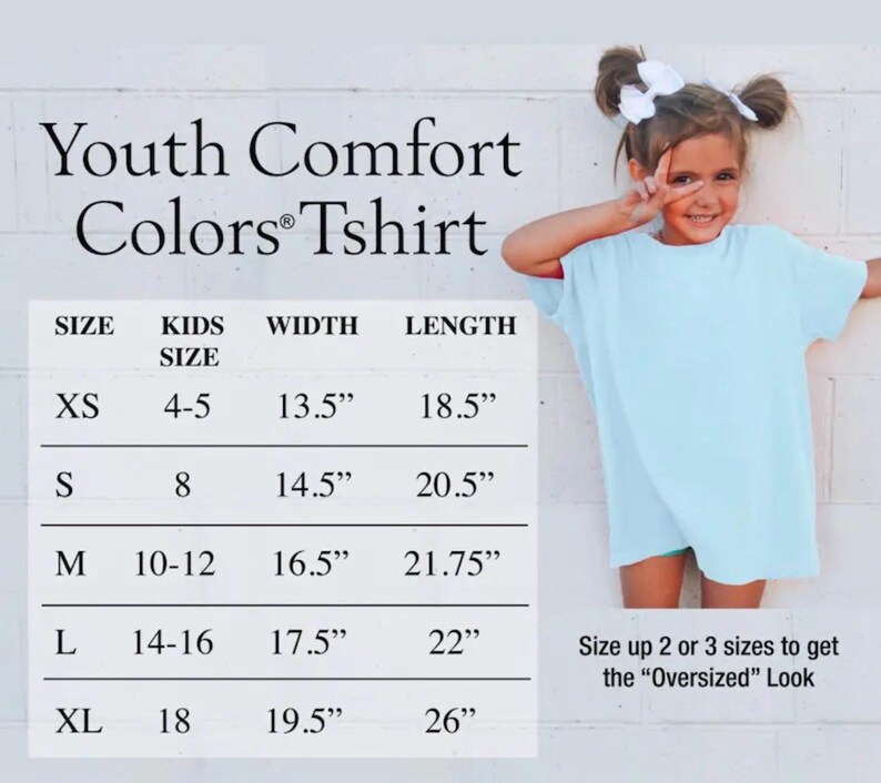May include: A light blue t-shirt with a size chart titled Youth Comfort Colors Tshirt. The chart lists sizes XS through XL with corresponding kids' sizes, widths, and lengths in inches. Text at the bottom suggests sizing up for an oversized look.