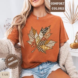 May include: An orange t-shirt featuring a patchwork maple leaf design. The leaf is composed of various patterns, including floral, plaid, and solid colors. The words "COMFORT COLORS" are printed at the top of the image.