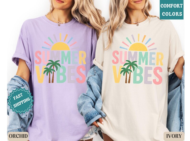 K&ouml;nnte beinhalten: Zwei T-Shirts, eines in Orchidee und eines in Elfenbein, mit dem Text "SUMMER VIBES" in bunten Buchstaben, einer Sonne und Palmen. Die Shirts haben eine lockere Passform, perfekt f&uuml;r den Sommer.