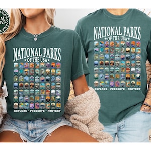 以下が含まれることがあります： アメリカの国立公園をすべて描いた白いグラフィックが施された緑色のTシャツ2枚。グラフィックには「National Parks of the USA」と「Explore - Preserve - Protect」の文字が書かれています。