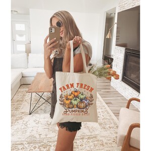 May include: A white tote bag with the text "Farm Fresh Pumpkins Hand Picked Daily" and a graphic of pumpkins.