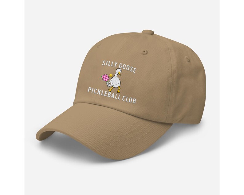 May include: A tan baseball cap with the text "Silly Goose Pickleball Club" and a cartoon goose holding a pickleball paddle.