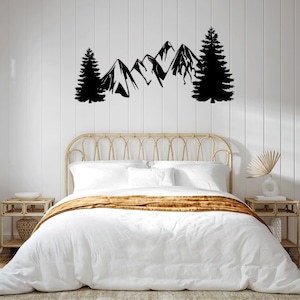 Può includere: Arte murale nero di montagne e pini sopra un letto con testiera intrecciata. Il letto ha biancheria da letto bianca e un runner dorato. Due piccoli comodini fiancheggiano il letto.