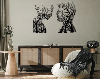 May include: Two black metal wall art pieces depicting human profiles with tree-like designs. The artwork is mounted on a light-colored wall above a dark wood cabinet. The room has a modern, minimalist aesthetic.