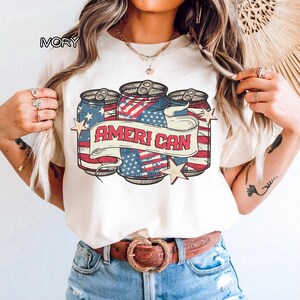 May include: A white ceramic mug with a black handle and the text "But First, Coffee" in a bold, black font. The mug is filled with a dark liquid, probably coffee, and rests on a light-coloured surface.