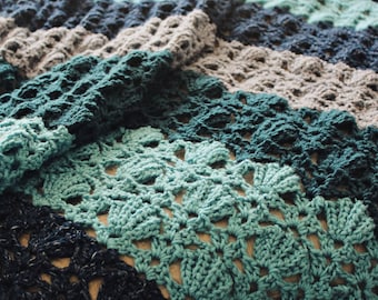 May include: A crocheted blanket with stripes of teal, blue, and gray. The blanket is made with a lacy stitch pattern.