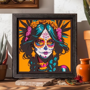 Op de afbeelding: Een vierkant ingelijst meerlaags papierkunstwerk met een gestileerd portret van een persoon met sugar skull-gezichtsbeschildering. Het ontwerp gebruikt levendige oranje, turquoise, roze en zwarte lagen om diepte te creëren.