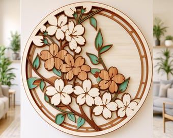 May include: A circular wooden wall art piece featuring layered cherry blossom branches with white and natural wood-toned flowers and teal leaves. The design is enclosed in a circular frame with a cutout pattern. The text studio TOKANO is visible.