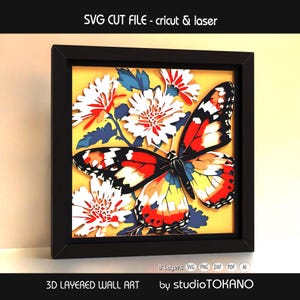 Può includere: Un'opera d'arte murale 3D incorniciata con una farfalla e fiori vibranti. La farfalla ha ali rosse, arancioni, nere e gialle. I fiori sono bianchi e rossi, su uno sfondo giallo. La cornice è nera. Il testo sull'immagine recita "SVG CUT FILE - cricut & laser" e "3D LAYERED WALL ART".