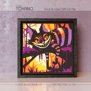 May include: A multi-layered paper art piece in a black frame featuring a grinning cat with orange eyes and purple striped fur perched on a branch. The background displays yellow and orange foliage. Text reads studio TOKANO Cricut & Laser SVG Cut File.