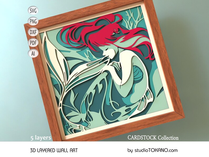 Op de afbeelding: Een 3D gelaagd wandkunstwerk met een zeemeermin met rood haar en een turquoise en witte staart. De zeemeermin wordt omringd door bladeren en de kunst is ingelijst in een houten lijst. De tekst "CARDSTOCK Collection" en "by studioTOKANO.com" is zichtbaar onderaan de afbeelding.
