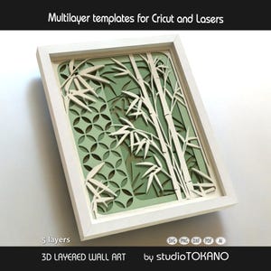 May include: A 3D layered wall art piece in a white frame featuring a bamboo design with five distinct layers. The artwork displays intricate cutouts of bamboo stalks and leaves against a geometric circular pattern in shades of light green.