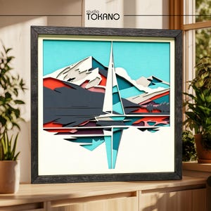 Könnte beinhalten: Ein quadratisches, gerahmtes, mehrschichtiges Papierkunstwerk mit einer stilisierten Berglandschaft und einem zentralen Segelboot. Das Design verwendet Türkis, Weiß, Dunkelgrau und Rot. Der Text "studio TOKANO" ist oben mittig aufgedruckt.