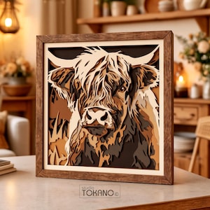 May include: A square, multi-layered wooden wall art piece featuring a detailed cutout of a Highland cow. The artwork uses various shades of brown, cream, and tan to create depth, all enclosed in a dark wood frame. The text "studio TOKANO" is visible.