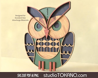 Puede incluir: Un búho de madera con patrones geométricos en tonos marrones, verdes y azules. El búho tiene un pico grande y ojos grandes. El texto "Designed for Standard Size Glowforge Materials" es visible en la imagen.